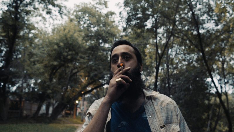 A man smokes a cigarette at dusk